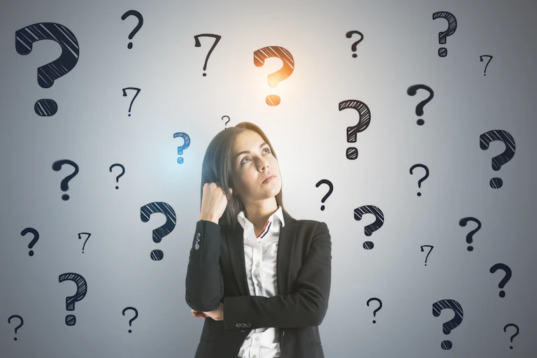 Woman looking up surrounded by question marks.
