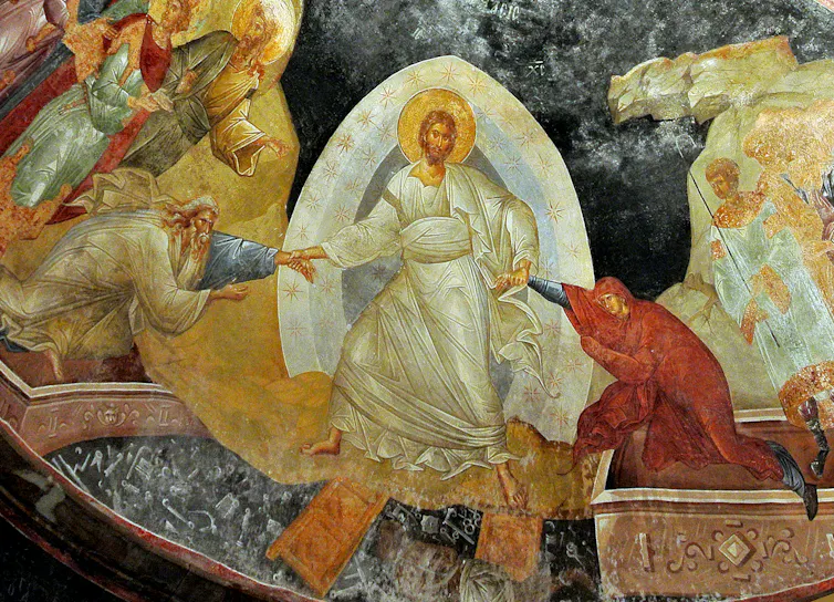 Jesus wearing a white robe, encased in white light, pulling two figures out of their graves as several others look on.
