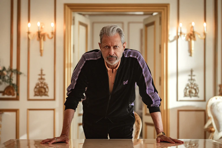 Jeff Goldblum in a tracksuit, stood in a luxurious room.