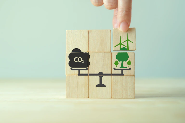 Des blocs représentent une balance pesant des émissions de CO₂ et des compensations carbone