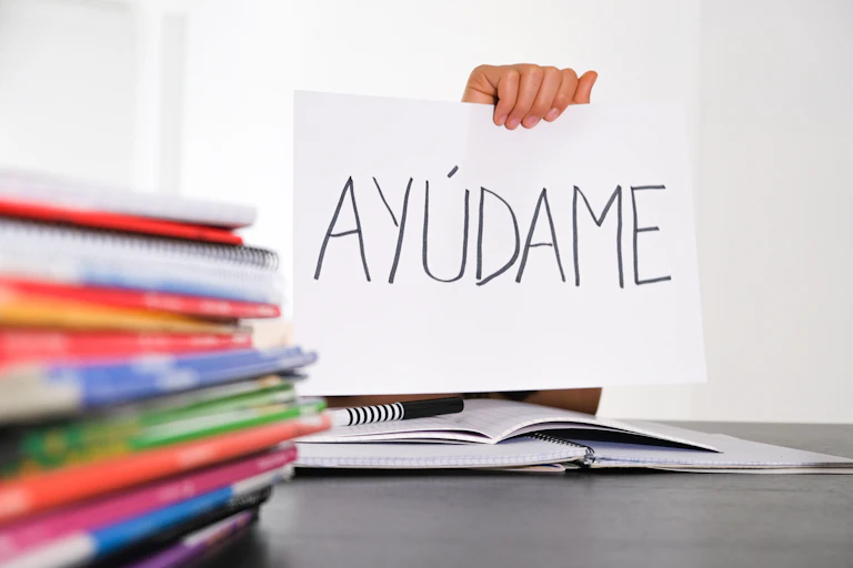 Hand holding sheet of paper with Spanish word 'Auydame'