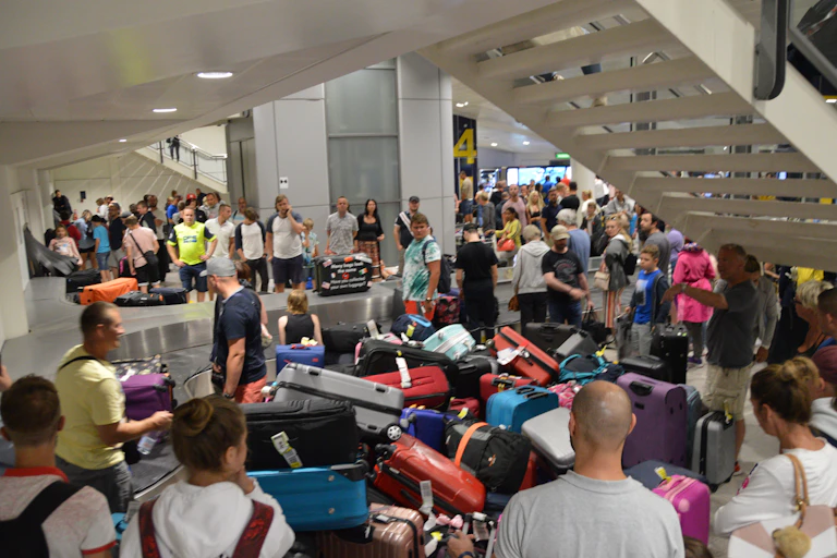 Passengers at an airport looking at piles of suitcases