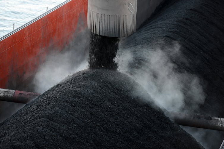 Coal falling out of a pipe into a barge.
