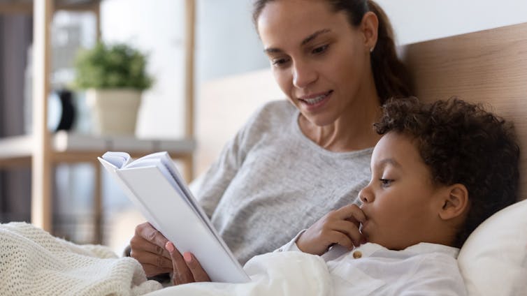 A parent with child and a book.