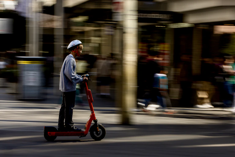 A young man rides a rental e-scooter through the Melbourne CBD
