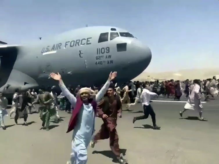Afghans running alongside departing US plane in 2021.