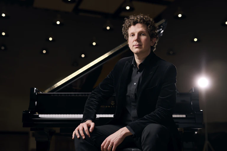 Gillham sits in front of a piano.