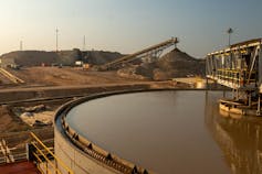 A giant mine with machinery and a large pond
