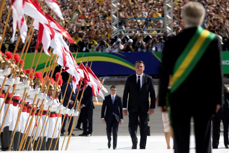 Jair Bolsonaro approaching his predecessor Michel Temer to receive the presidential band.