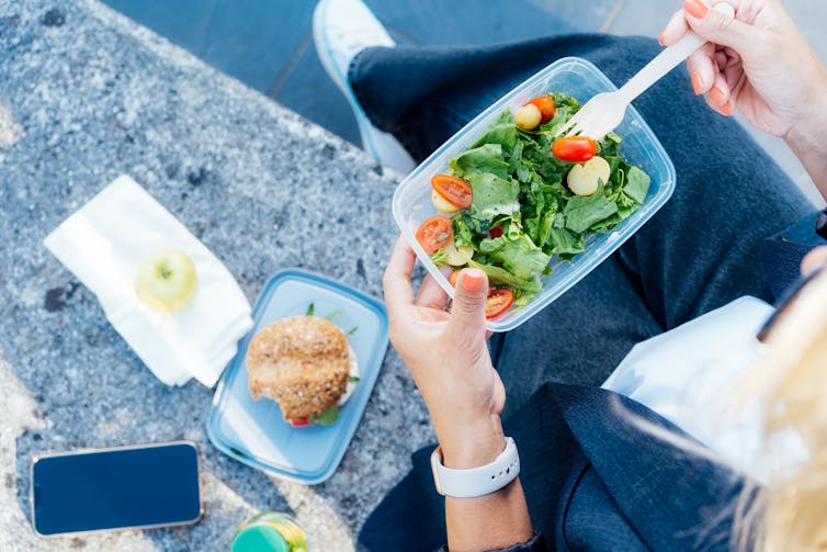 overhead view of a woman eating a salad outside