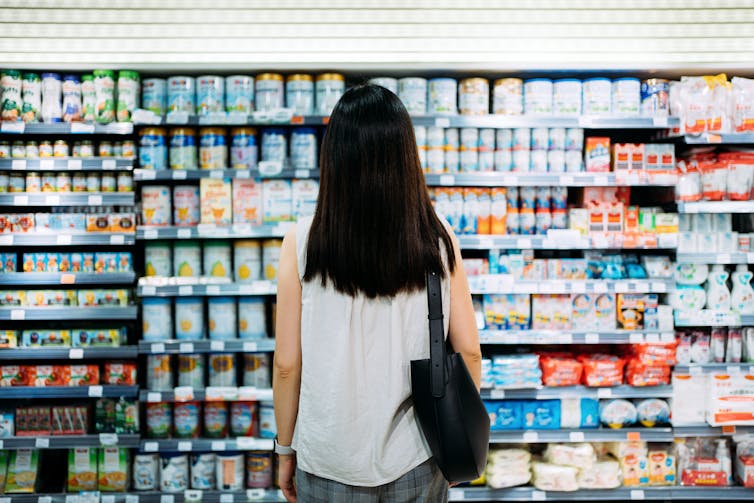 A woman looking at a supermarket shelf of baby formula