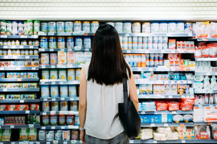 A woman looking at a supermarket shelf of baby formula