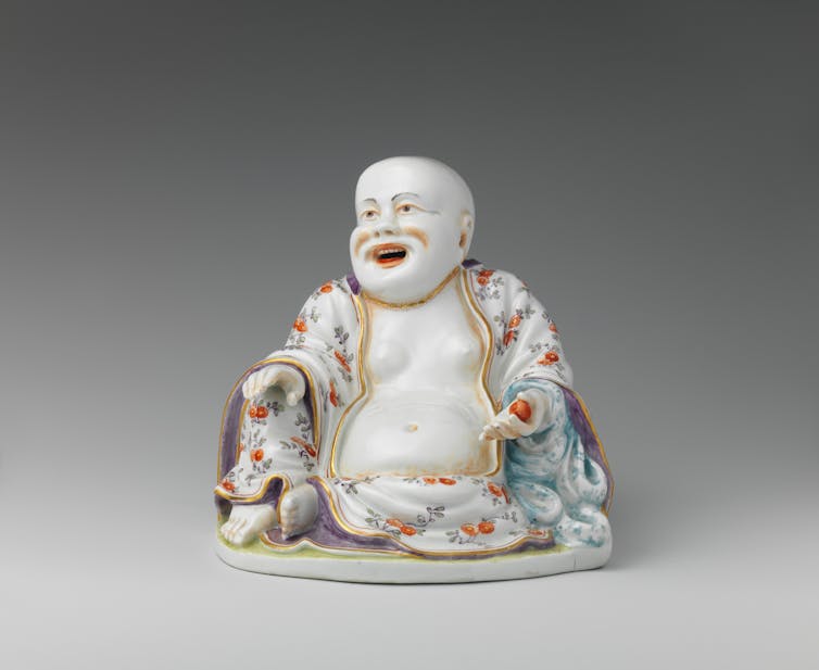 Statue of a laughing, seated monk, draped in a robe with colorful flowers.