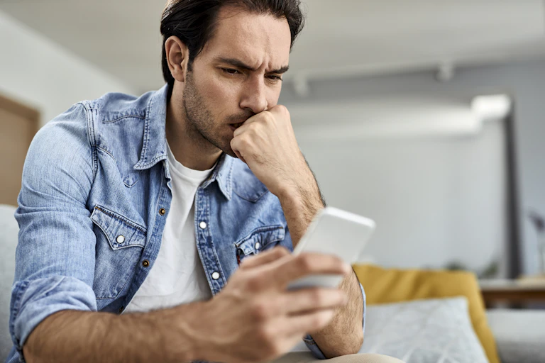 a man looks at his phone with a puzzled expression