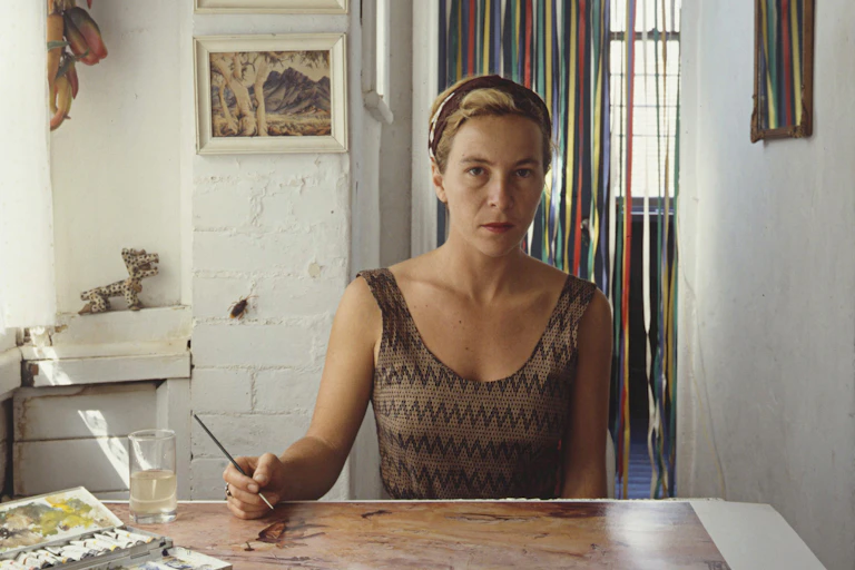 A woman sits at a table, painting