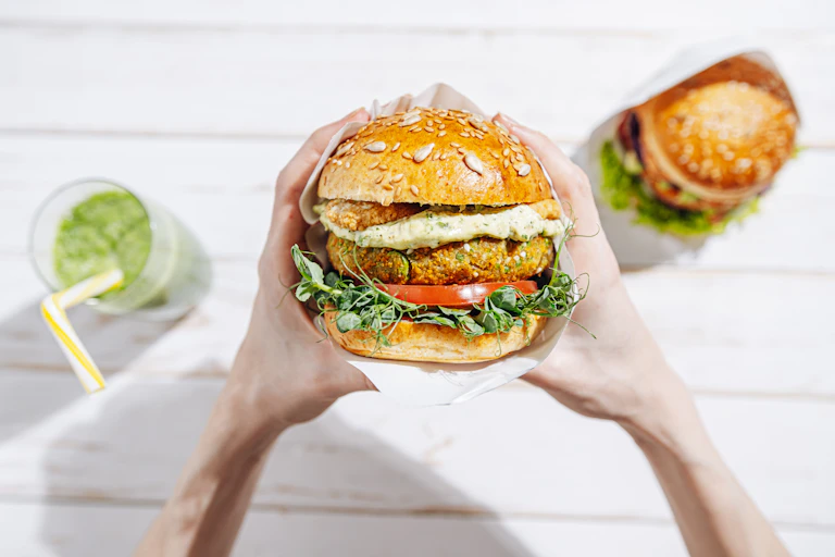 Hands gripping a veggie burger.