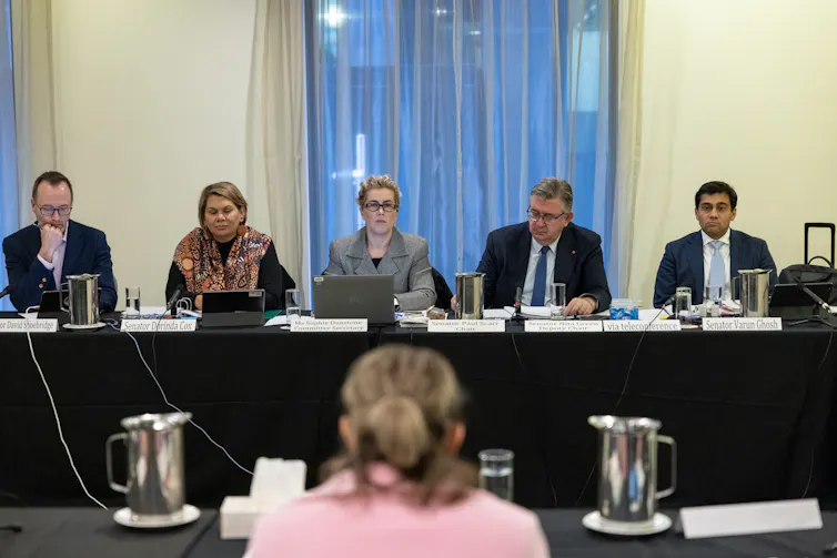 A panel of people behind a black desk
