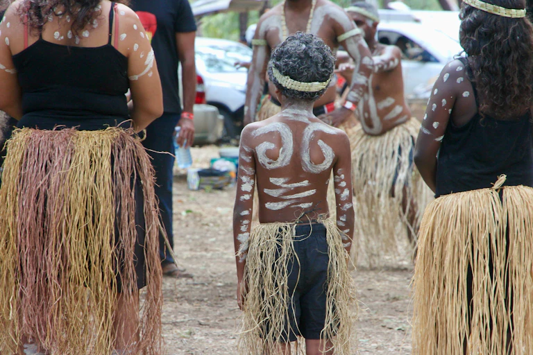 An Indigenous woman stands next to two Indigenous children
