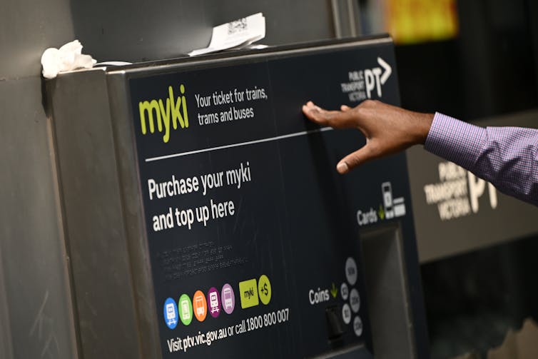 A person tops up their travel card at a machine