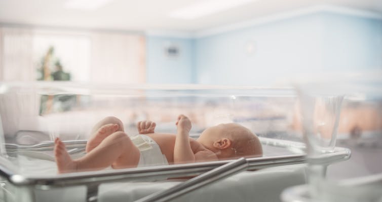 A baby in a hospital crib.