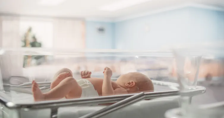 A baby in a hospital crib.