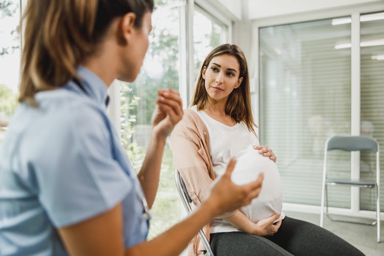 A nurse talks to a pregnant woman.