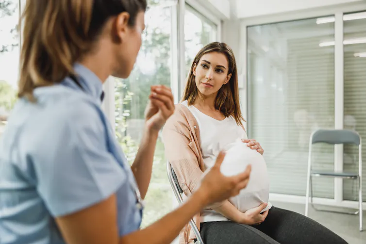 A nurse talks to a pregnant woman.