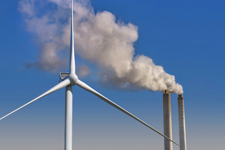 Turbina eólica y chimeneas que generan humo.