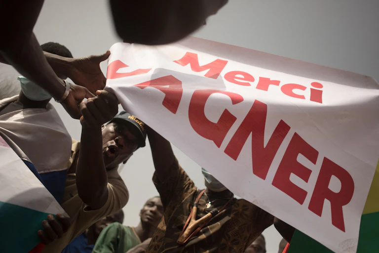 A group of people waving a white banner with red prints