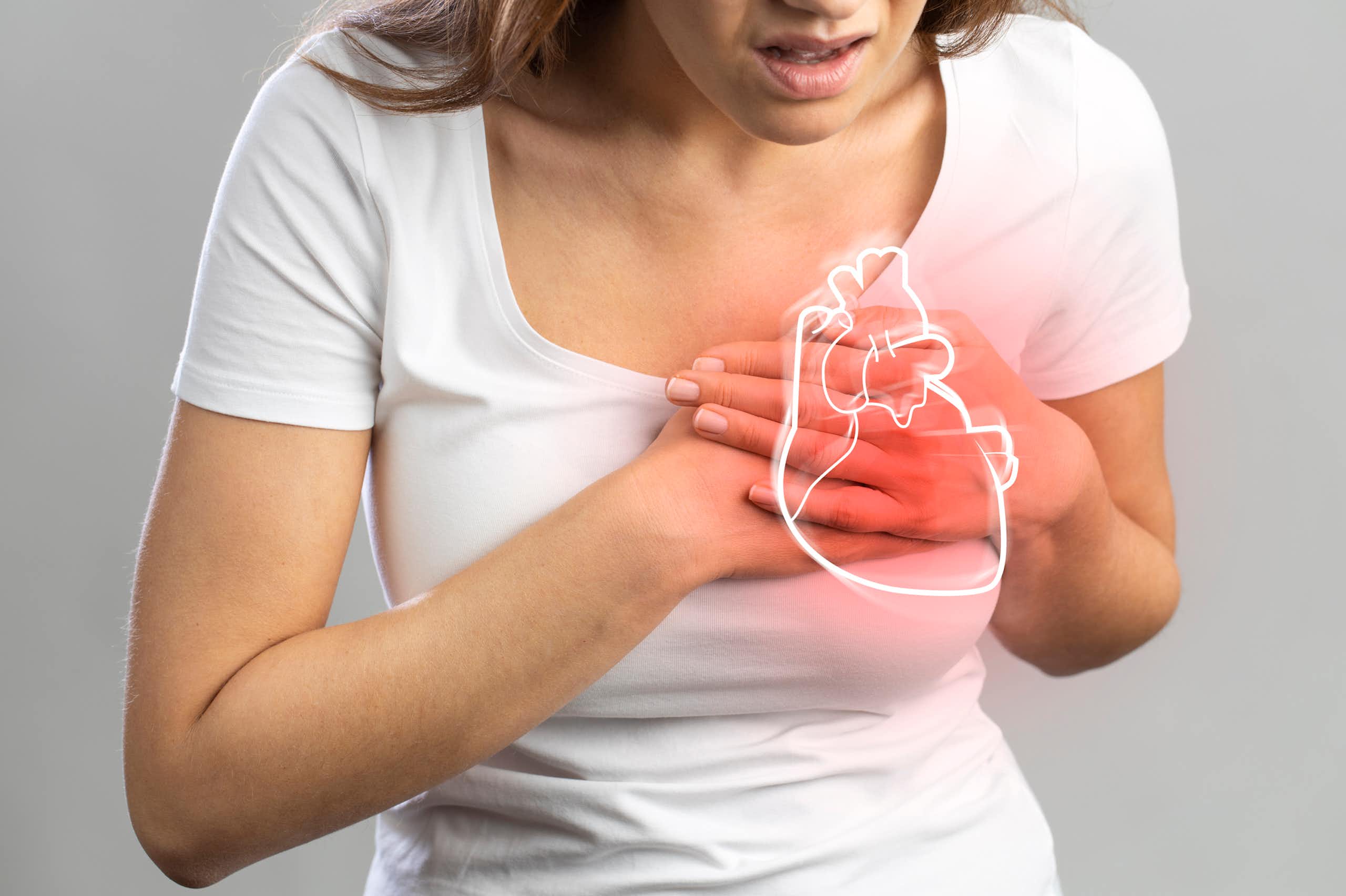 Person with hands over chest in pain, beneath a glowing outline of a heart