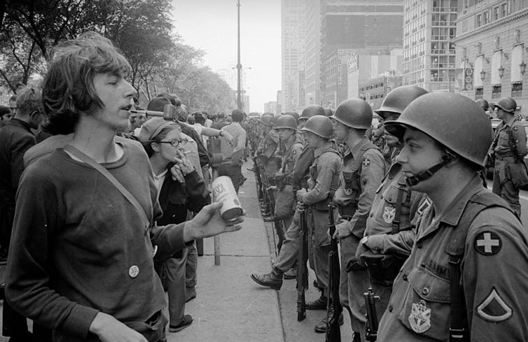 black-and-white photograph of rows of police and protestors facing off