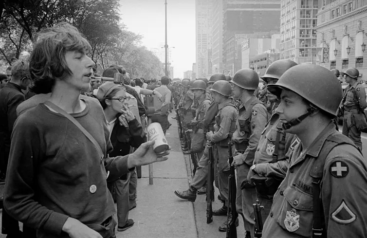 black-and-white photograph of rows of police and protestors facing off