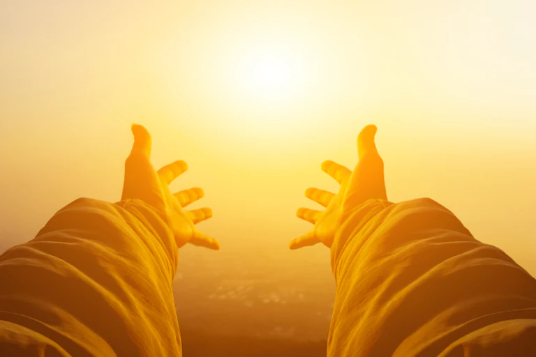 Pair of outstretched arms reaching towards Sun