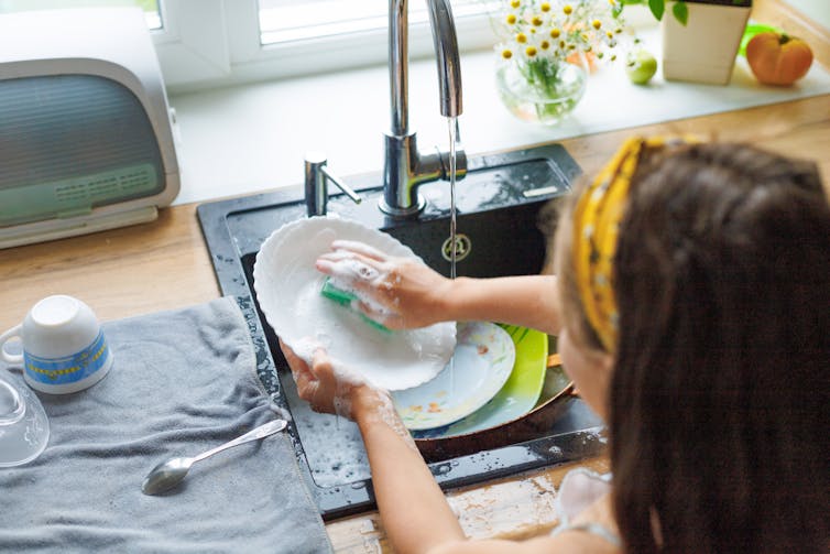 A woman washing dishing in the sink