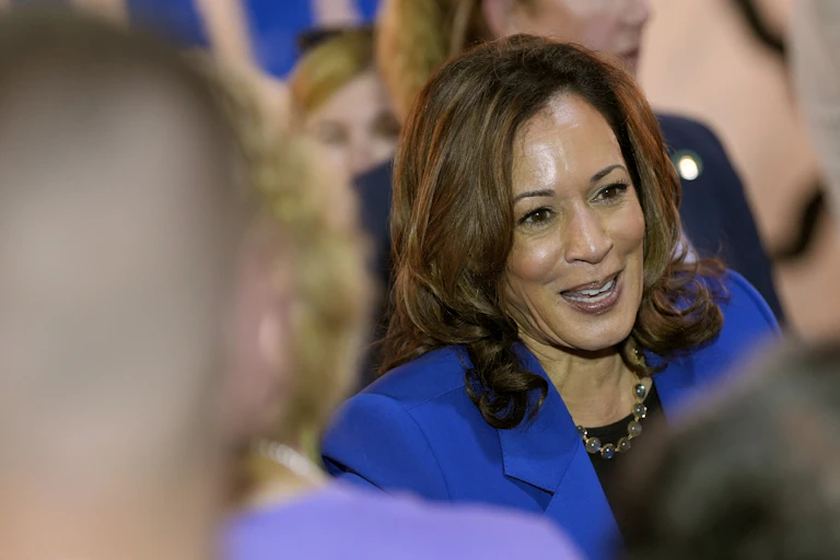 A woman in a blue blazer shakes hands in a crowd