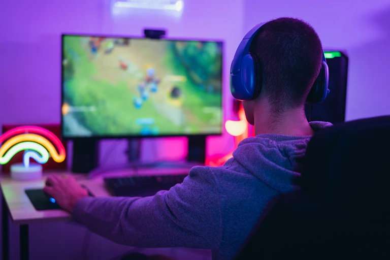 young person playing video game at desk with purple light