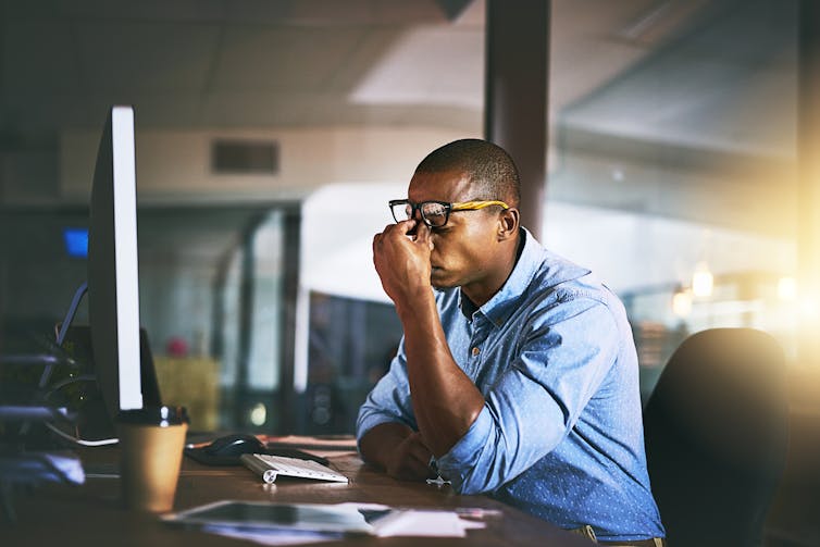 A man sitting at a computer appears stressed.