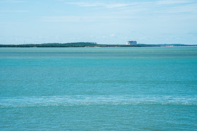 blue ocean with land and infrastructure in distance