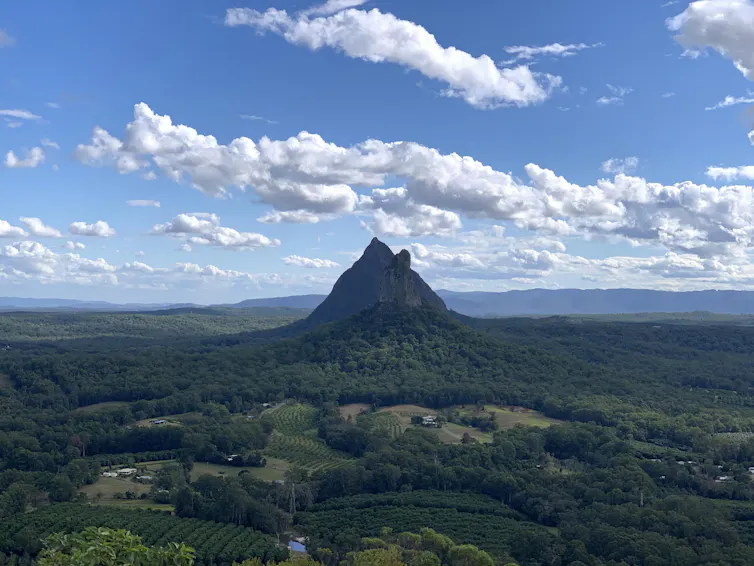 Photo of a black cone rising from a forested plain.