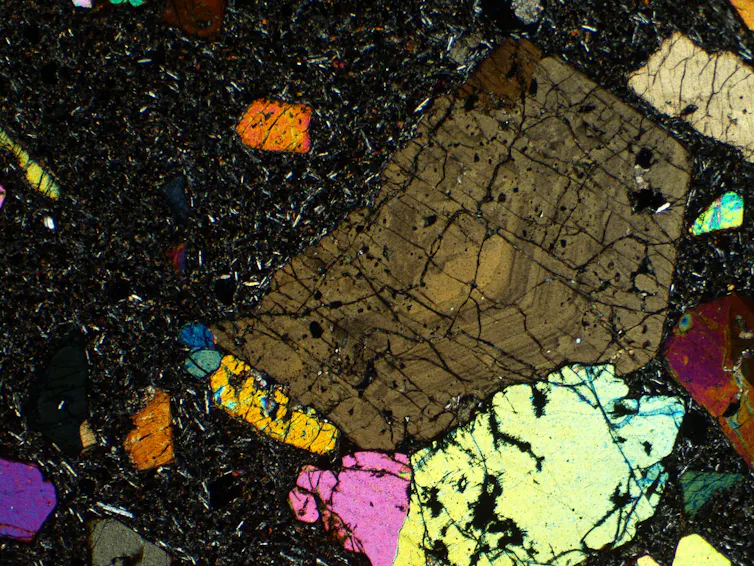 Photo of multicoloured crystals in black rock.