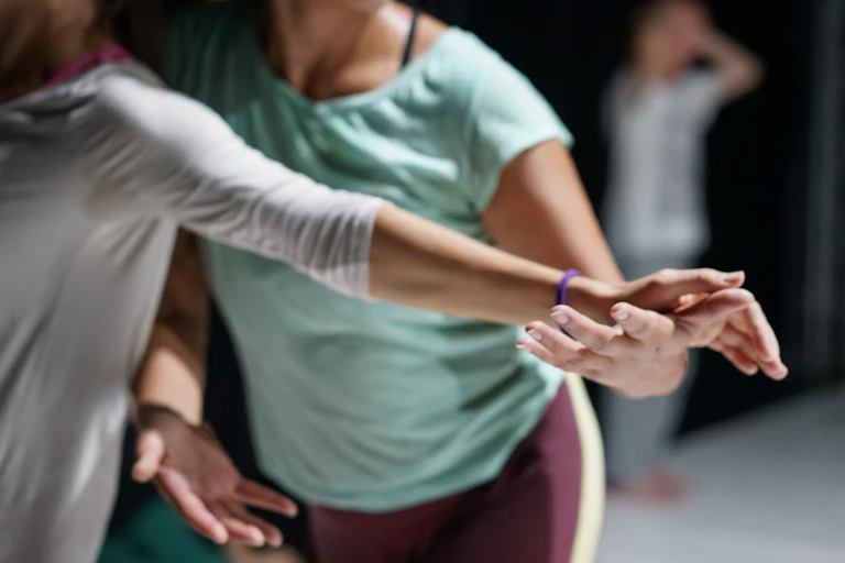 two people's bodies are in frame wearing stretchy clothes and dancing in studio setting
