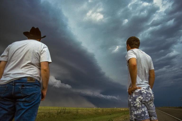 two men looking at a dark stormy sky