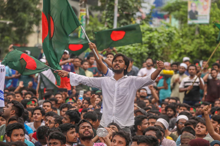 A protester holds the national flag of Bangladesh as he participates in a protest.