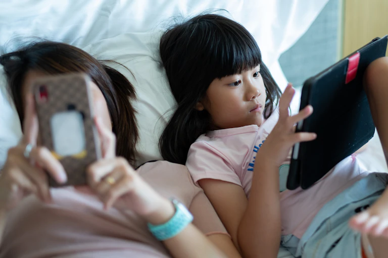 A young girl watches something on an iPad.