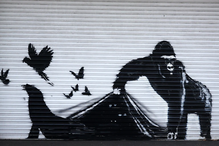 A mural of a Gorilla lifting a curtain for animals to escape from behind shutters.