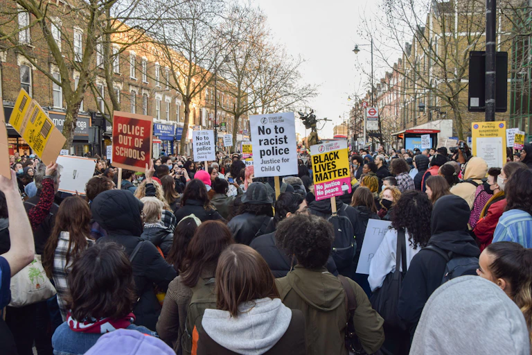 Crowd holding signs including one saying 'no to racist police'