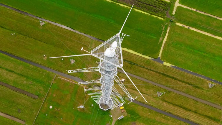 aerial shot of tall metal tower, green fields