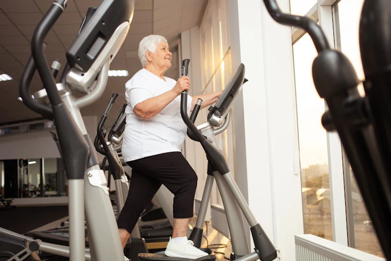 Uma mulher idosa se exercita em um aparelho na academia.