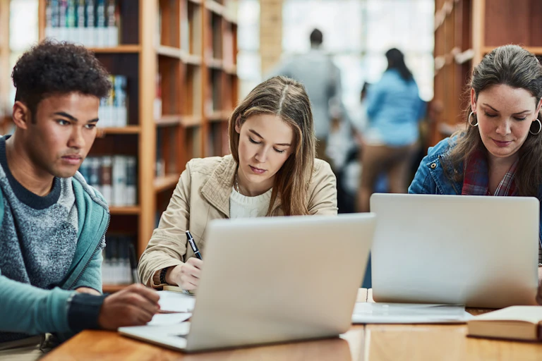 Trois jeunes étudient à la bibliothèque