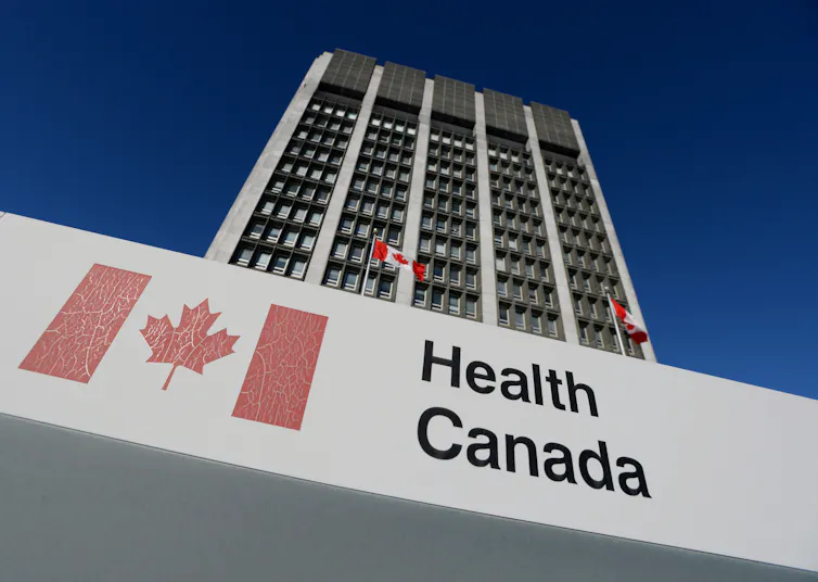A sign that says 'Health Canada' displayed in front of a high-rise building with Canadian flags on it
